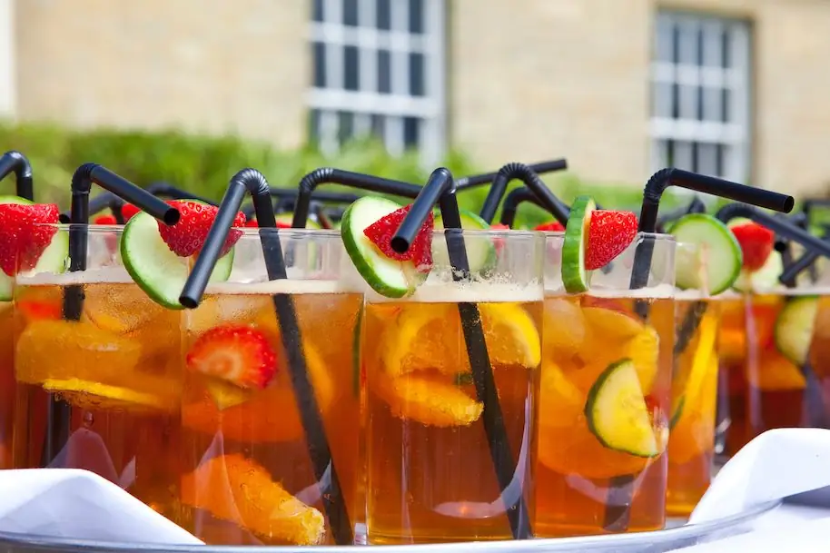 Бокалы Pimms на белой скатерти на вечеринке в саду Бокалы Pimms на белой скатерти на вечеринке в саду