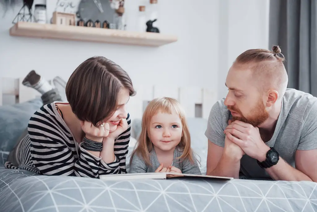 Родители читают дочери сказку на ночь Родители читают дочери сказку на ночь